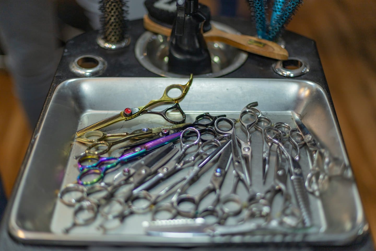 Professional hairdressing scissors neatly organized in a metal tray.