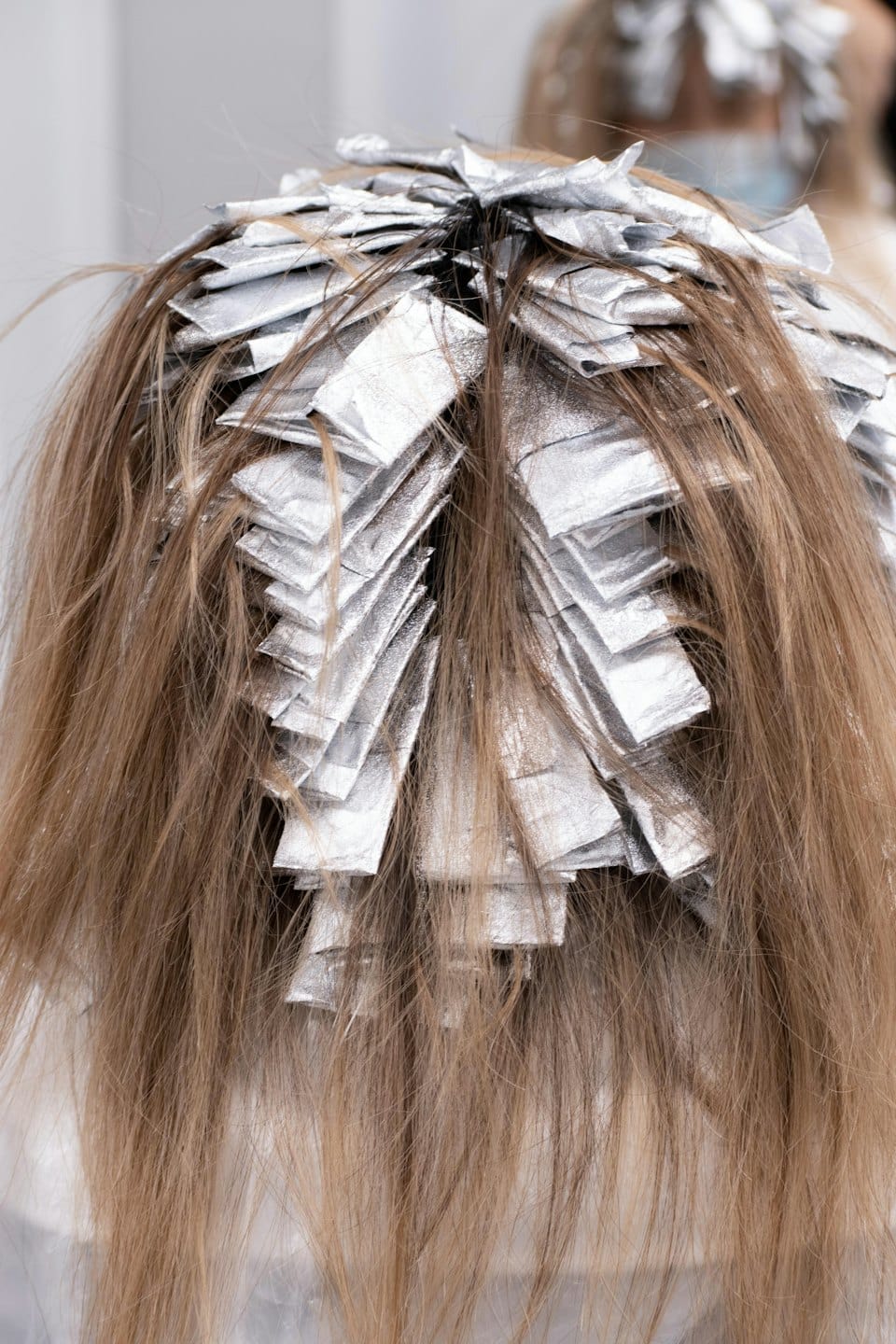 Hairdresser adding highlights with foil packets.