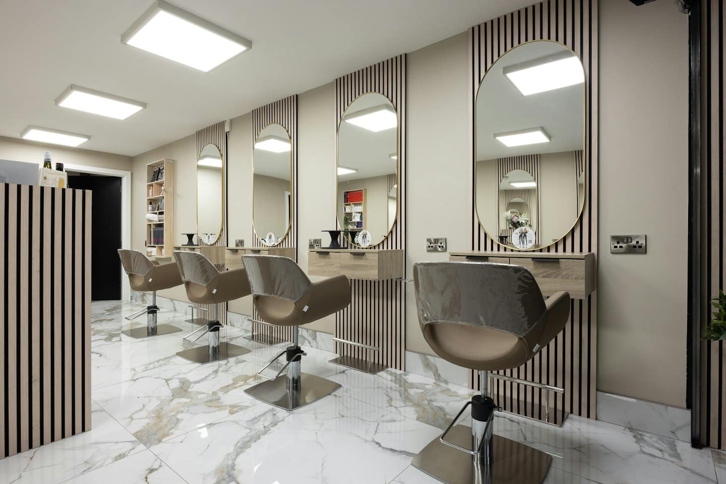 Contemporary hair salon styling stations with gold mirrors and wood cabinets.