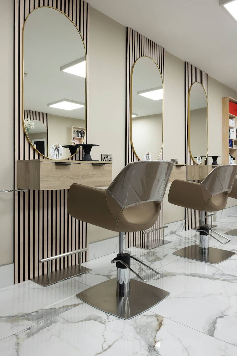 Unoccupied modern hair salon styling stations with gold accents.