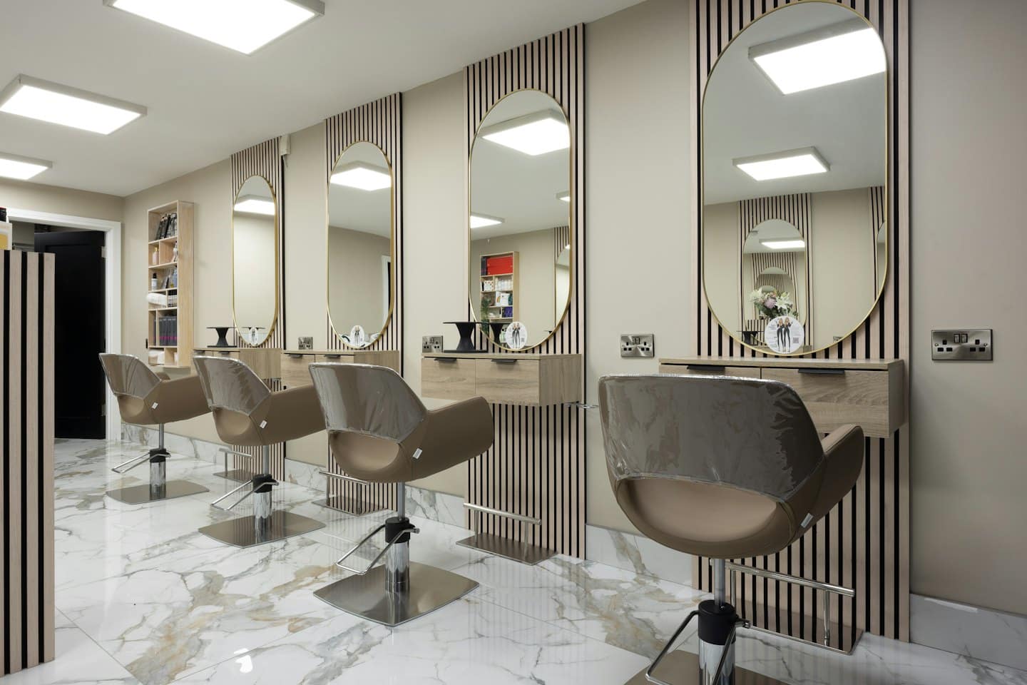 Empty modern hair salon with styling stations and marble floors.