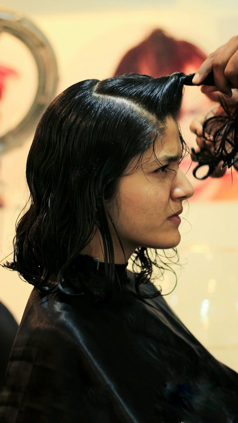 Stylist carefully combing the wet hair of a client.
